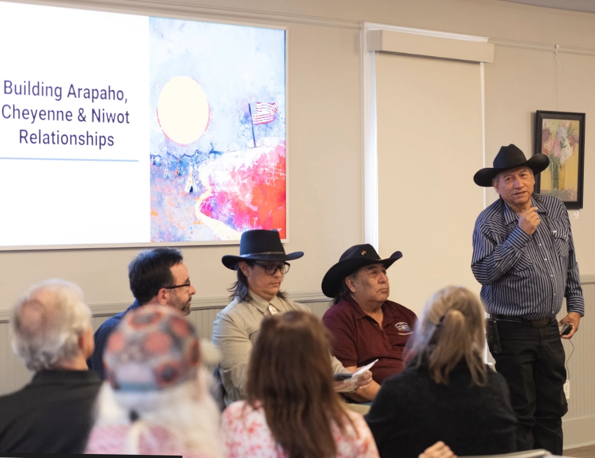 Southern Arapaho Elder Fred Mosqueda speaking at the Niwot community gathering with Southern Cheyenne Elder Chester Whiteman seated nearby